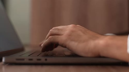 Nahaufnahme nicht erkennbarer männlicher Hände, die den Laptop ausschalten und den Deckel des Computers am Schreibtisch schließen