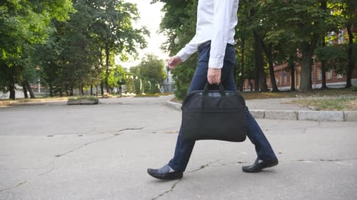 Legs of Unrecognizable Businessman with Briefcase Stepping Through City Park Successful Company