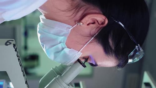 Mikrobiologin schaut ins Mikroskop im Labor für medizinische Wissenschaften