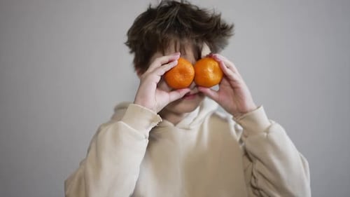 Child Holding Tangerines Up to Their Eyes