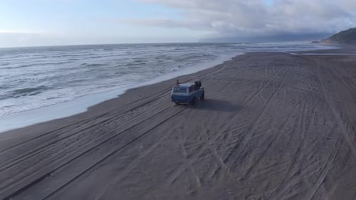 Aerial View of Group of Friends Driving on Beach in Vintage Vehicle Aerial