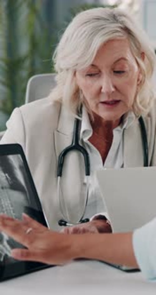 Woman Doctor Explains X-Ray to Patient in Office