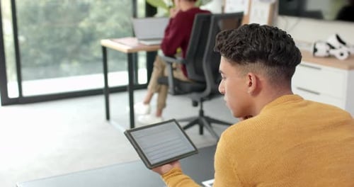 Utilisation d'une tablette, homme travaillant à domicile tandis que son partenaire travaille sur un ordinateur portable