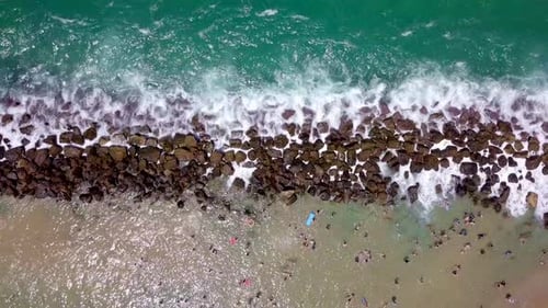 Tropical beach with people enjoying the calm water behind a wave breaker