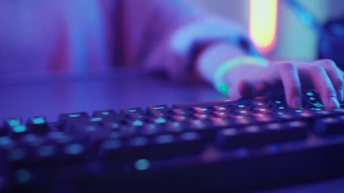 Close-up on the Hands of the Girl Gamer Playing in the Video Game Using Keyboard. Female Hacker Bre