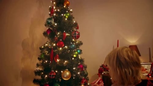 Child decorating Christmas tree with colorful ornaments indoors