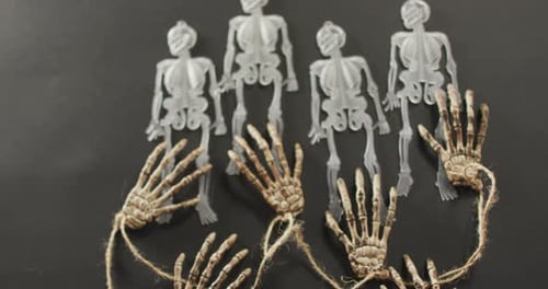 Multiple skeleton toys and skeleton hands with copy space on grey background