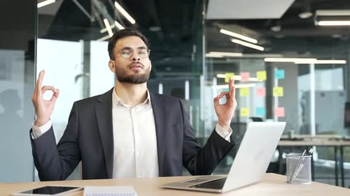 Geschäftsmann im formellen Anzug meditiert mit geschlossenen Augen während einer Pause am Arbeitsplatz