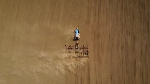 Aerial Top View Blue Tractor Plowing Farm Soil in Field for Sowing Crops