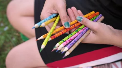 Young Adult Holding Colorful Patterned Pencils Outdoors