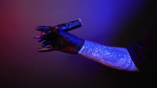 Tattooed Arm Holding Tattoo Gun Close Up