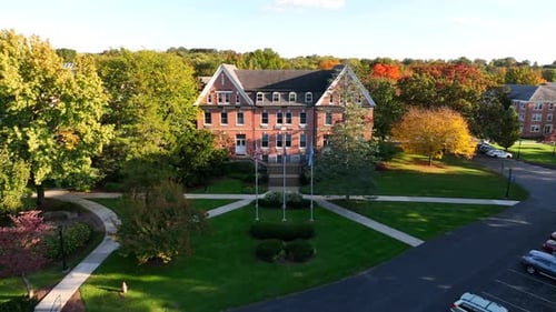 College campus in USA. Rising aerial over Old Main Library building during colorful autumn golden ho