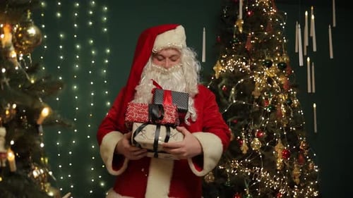 Man Dressed as Santa Holding Christmas Gifts Indoors