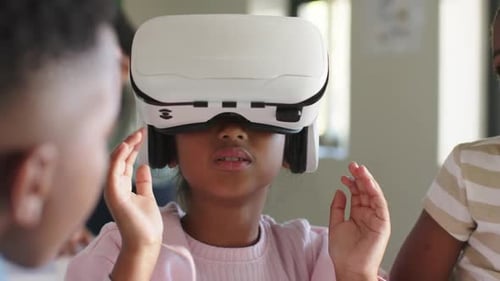 Students watching girl in pink top lifting white VR headset, adjusting, removing for classroom demo
