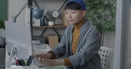 Young Adult Typing at Computer in Modern Office