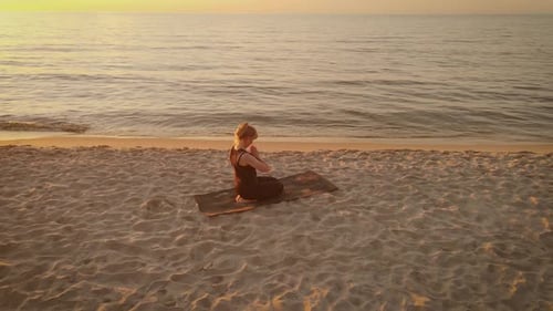 Woman Practicing Yoga at Beach During Sunrise
