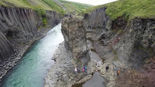 Aerial Of Hikers Exploring Stuðlagil Ravine. Dolly Back Shot