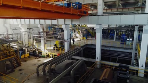 Anlagenwerkstatt mit Rohrleitungen und laufendem Arbeiter in der Werkstatt