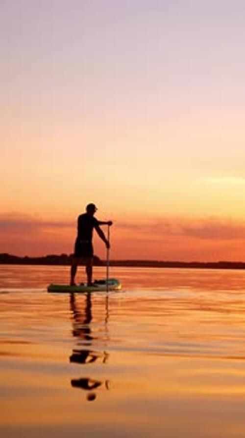 Person Paddle Boarding in the Sunset on Water