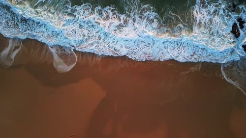 Stunning Aerial Coastal View Showcasing Waves Crashing Gracefully on Golden Beach Sand