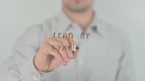 Writing the words Lead by Example on Glass