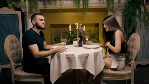 Young couple guy and girl sitting in an Italian restaurant sweetly chatting and drinking wine