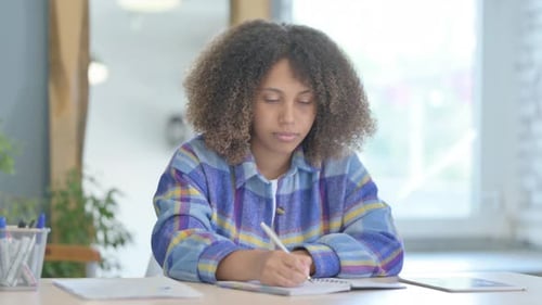 Woman Writing in Notebook at Desk Indoors