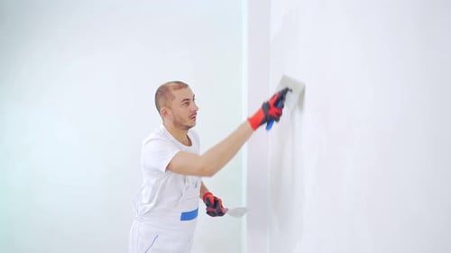 Young Adult Man Plastering a White Wall