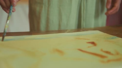 Artist Painting on Canvas with Brush in Studio