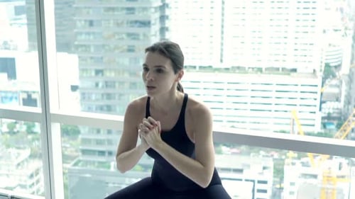 Woman doing squats on mat in urban apartment