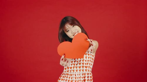 Happy Woman Holds Valentine Heart on Red Background