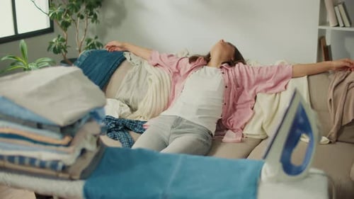 Tired Young Woman Falls on the Sofa From Weakness After Ironing the Laundry