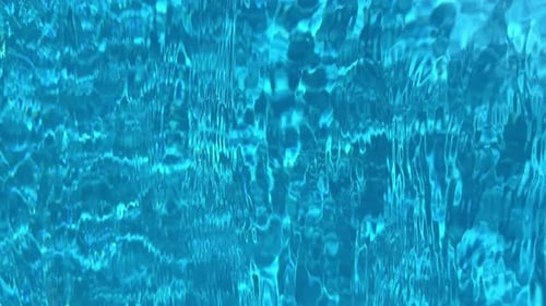 Nahaufnahme des hellblauen Schwimmbadwassers während des Tages mit plätscherndem Wasser, das für Interessantes sorgt