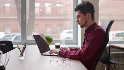 Young Adult Typing on Laptop in Urban Office