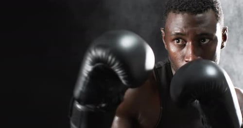 African American boxer training intensely in the gym on a black background