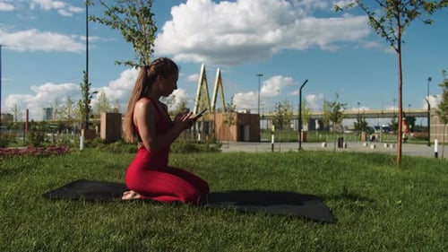 Woman Using Phone on Yoga Mat in Urban Park