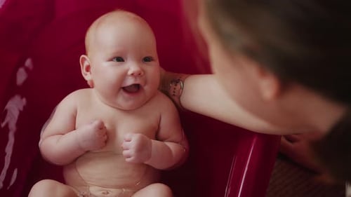 Mother Bathes Her Baby in Pink Bathtub Top View