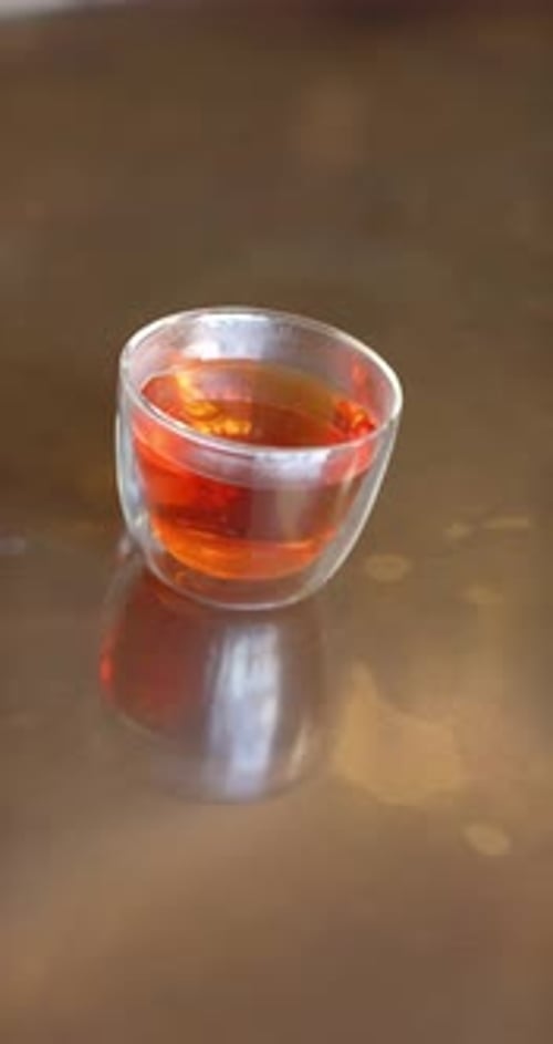 Vertikales Video: Die Kamera ist geneigt, um Dampf und warmes Leuchten aus der Glasschale auf dem braunen Tisch sichtbar zu machen