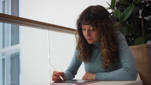 Woman Designer Drawing on Tablet with Stylus in Modern Office