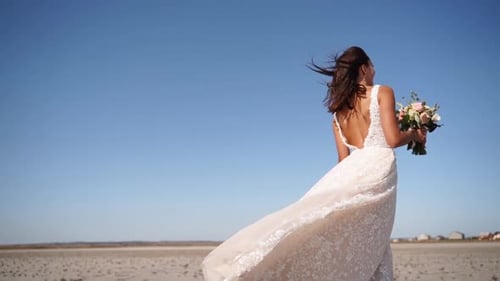 Pretty Woman in Gorgeous Wedding Dress Walking at Desert Landscape Windy Weather Elegance Bride with