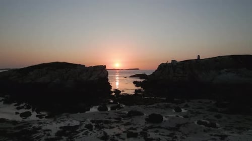 Sunset drone shot flying through two cliffs at Baleal beach Portugal.
