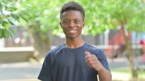 Young Adult Smiling and Giving a Thumbs Up