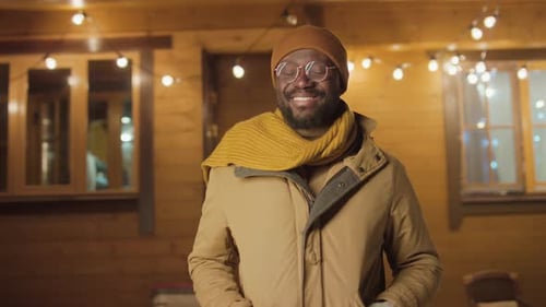 Man Smiling at Night near Warmly Lit Building