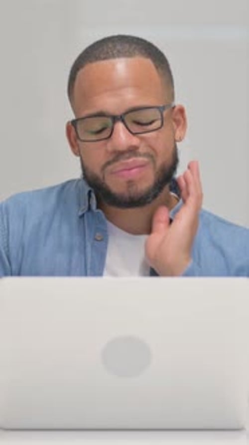 Man with Neck Pain Massaging Neck At Computer