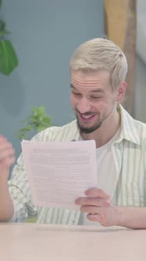 Modern Young Man Celebrating Success while Reading Documents in Office