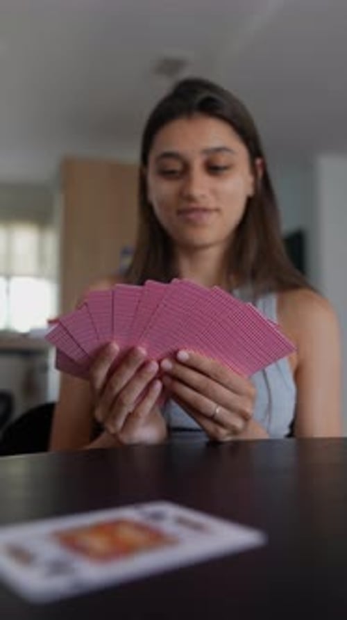 A Woman Engaging in a Card Game at Her Home Enjoying the Activity with Focus and Excitement