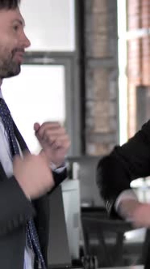 Businesspeople bump elbows in celebration at the office.