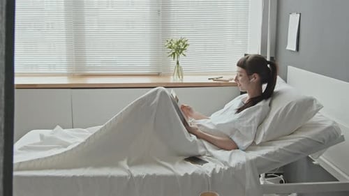 Female Patient In Hospital Watching Movie on Digital Tablet