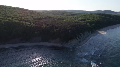 Beach Between a Ledge Covered with Vegetation and a Black Sea Under a Clear Blue Sky