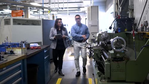 Manager gives factory tour to visitor walking through the production line